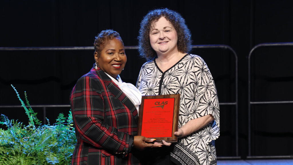 Dr. Regina Thompson and a Sheffield Education Foundation representative hold the Little Red School House Award plaque on stage at the 2026 CLAS Convention.